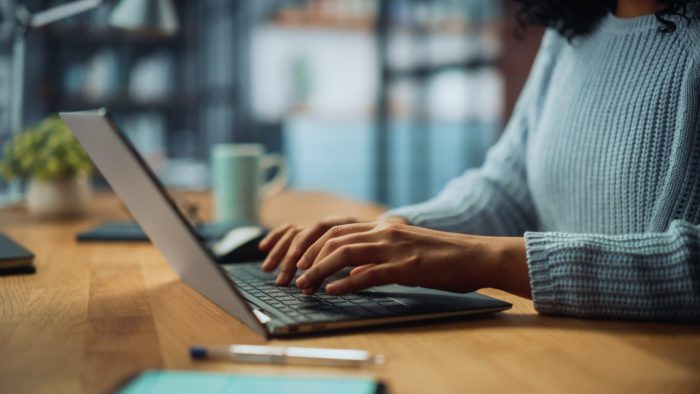 Close Up on Hands of a Female Specialist Working on Laptop Computer at Cozy Home Living Room while Sitting at a Table. Freelancer Woman Chatting Over the Internet on AI chat.